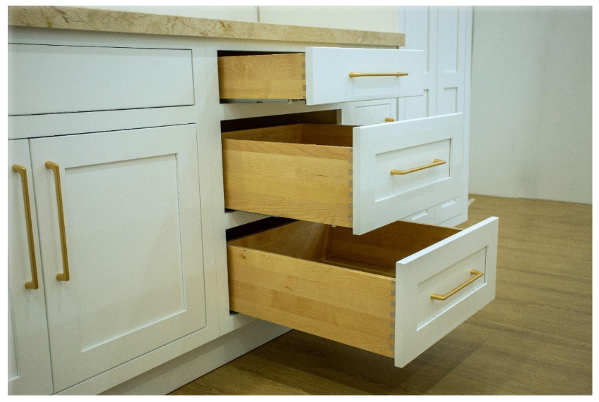 Close up of inset cabinet drawers open showing dovetail construction solid wood drawer boxes and gold bar pulls