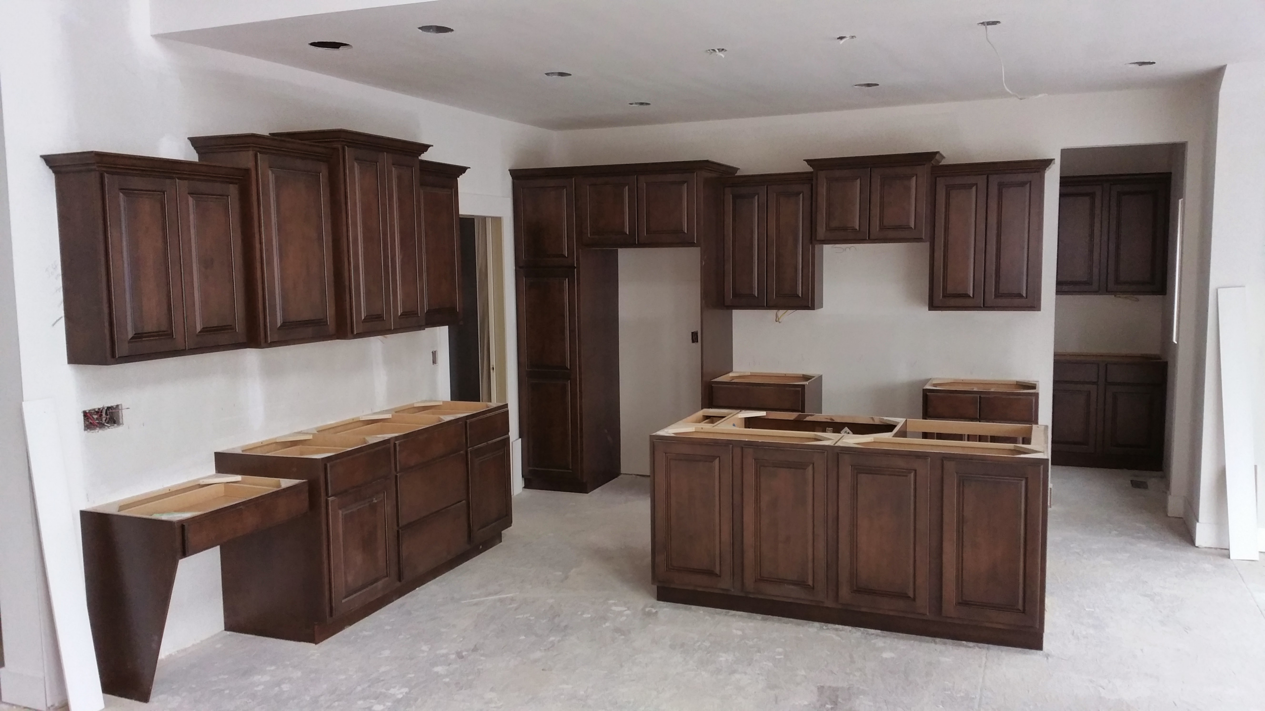 Complete L-shaped kitchen cabinet installation showing a full working kitchen layout